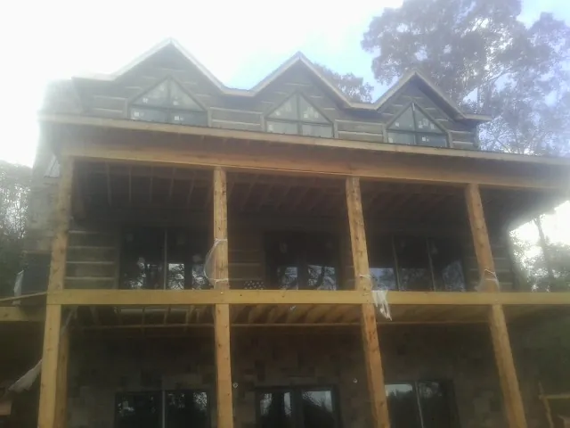 Dormers and porch framing on a large log home under construction — Roof Coating work by our crew in Hyde Park