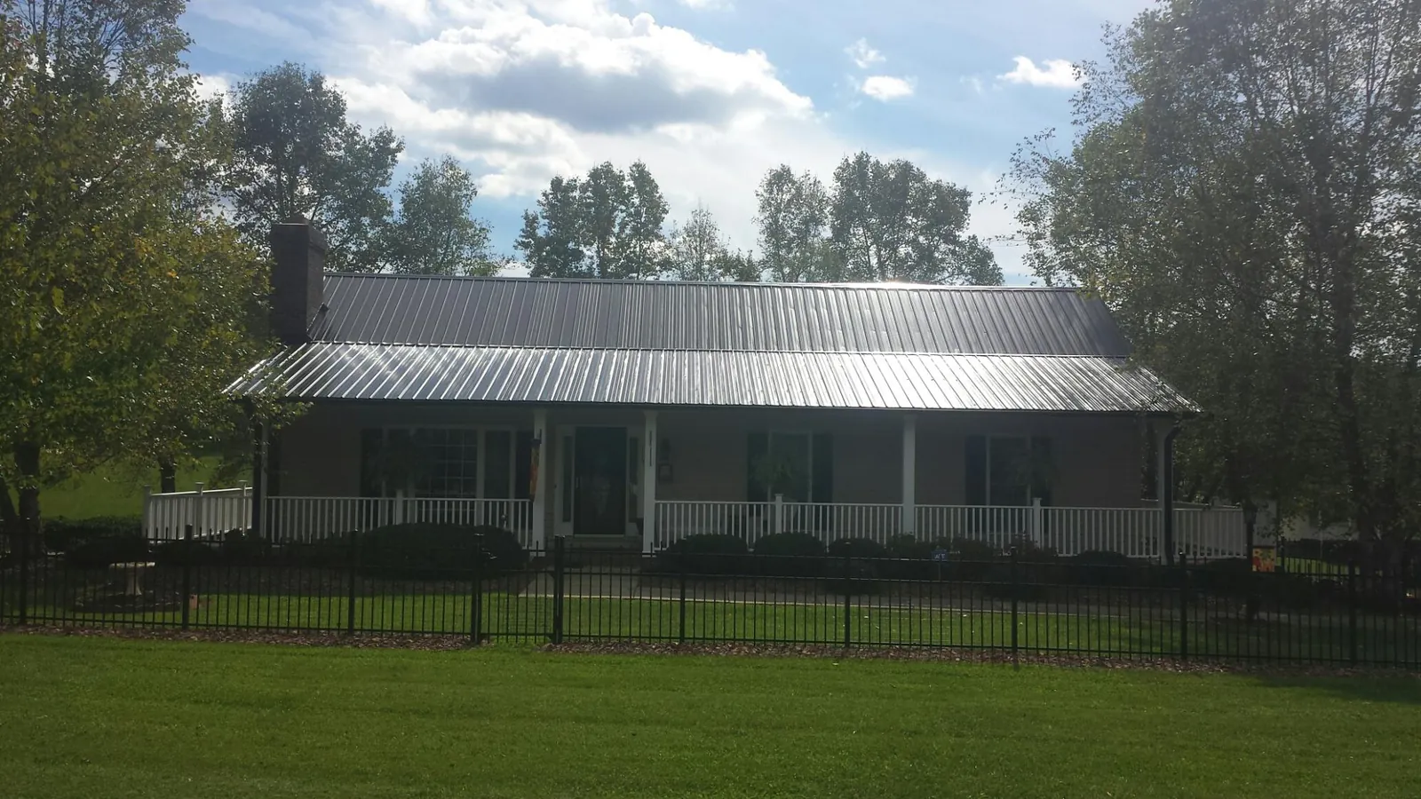 Gray metal roof on a brick ranch with a full width front porch — Gutter Guard Installation work by our crew in Hyde Park